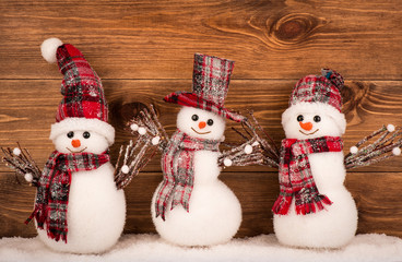 Christmas decorative snowmen on the brown wooden background.