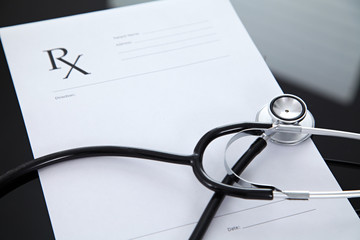 Stethoscope and prescription, black reflective background