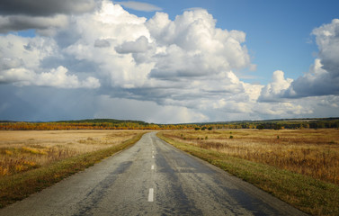 The road through the field on a background of beautiful sky