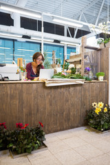 Florist Using Laptop At Counter In Flower Shop