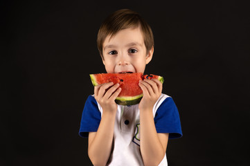 little boy eating watermelon isolated on black background
