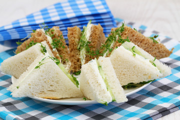 Traditional white and brown cream cheese and cucumber sandwiches and checkered napkins
