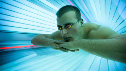 Man tanning bed in solarium