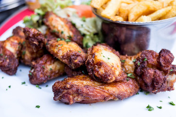 Chicken wings with sauce and golden French fries potatoes