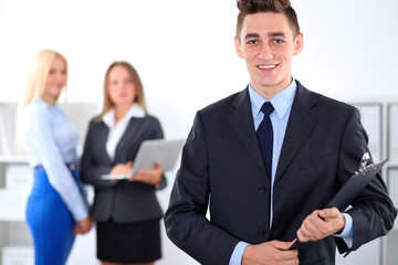 Fototapeta premium Cheerful business man in office with colleagues in the background, sturt-up team