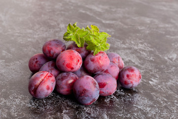 Fresh Dark Plums on black Table and mint