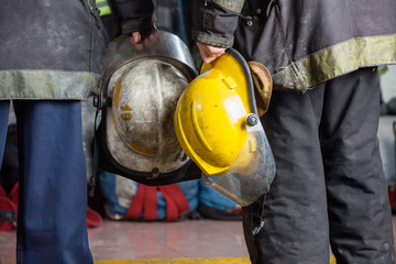 Obraz premium Firemen Holding Helmets At Fire Station