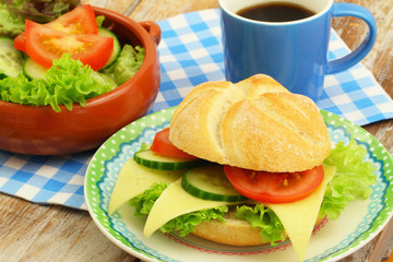 Lunch consisting of cheese roll, green salad and black coffee
