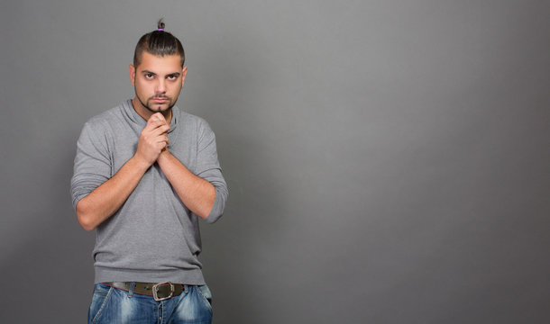 Fashionable hipster man with clasped hands in studio