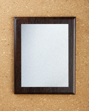 Wooden plaque with silver plate on cork background.