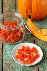 Homemade candied pumpkin pieces in glass jar and white plate wit