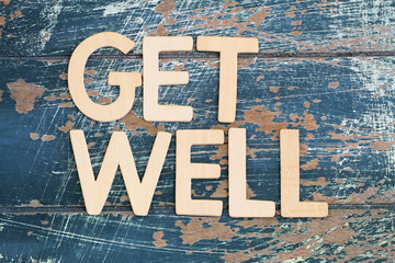 Get well written with wooden letters on rustic wooden surface
