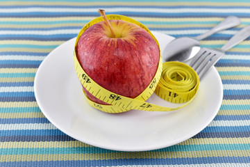 Red apple and yellow measuring tape concept  for healthy diet and body weight control.