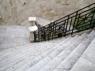long staircase descent in gray marble with black iron railing. Bastione Cagliari