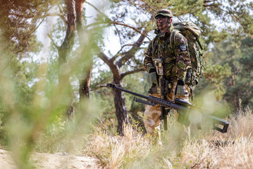 Armed soldier with sniper rifle in the forest/The armed soldier in uniform with  large caliber sniper rifle during training exercise in forest