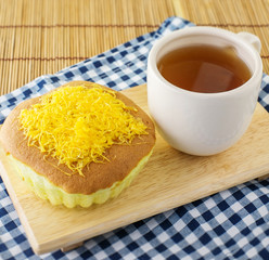 golden egg cake with hot tea on the wood table