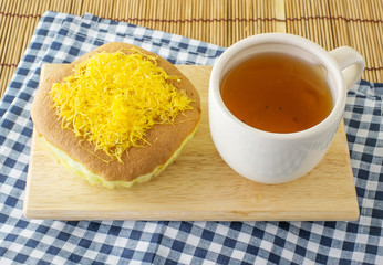 golden egg cake with hot tea on the wood table