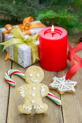 Christmas composition with gift box, gingerbread man, candy canes and candle, closeup