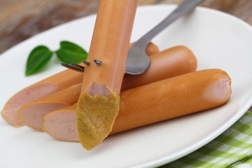 Frankfurter with mustard on fork, closeup
