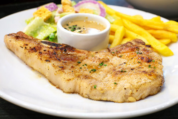 pork chop steak with salad and french fries on white dish