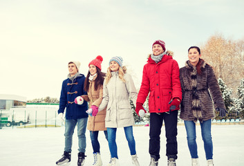 happy friends ice skating on rink outdoors