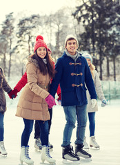 happy friends ice skating on rink outdoors