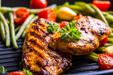 Grilled chicken breast in different variations with cherry tomatoes, green French beans, garlic,...