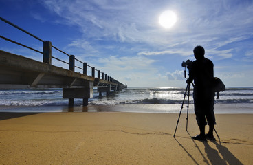 Silhouette of a photographer shooting the wooden bridge after su