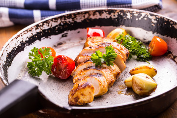 Grilled chicken breast in different variations with cherry tomatoes, green French beans, garlic, herbs, cut lemon on a wooden board or teflon pan. Traditional cuisine. Grill kitchen. 
