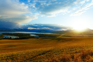 Beautiful landscape, yellow meadow and lake with mountains 