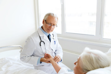 doctor checking senior woman pulse at hospital