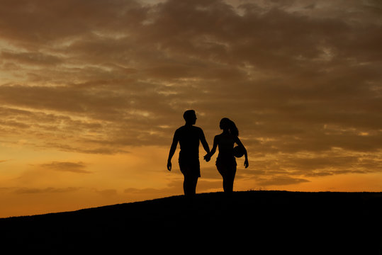 Loving couple of sportsmen walk on the evening hills.