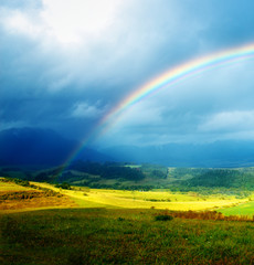 Obraz premium meadow and lake with mountain on background a rainbow 
