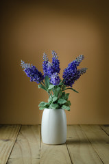 Lavender flowers in white vase on a brown background