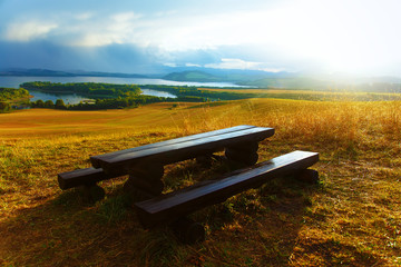 Obraz premium Beautiful landscape. Wooden bench in the meadow, and lake 