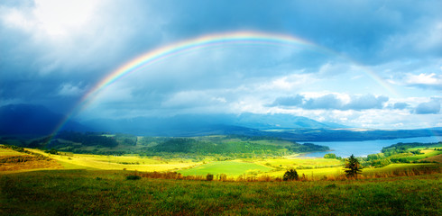  meadow and lake with mountain on background  a rainbow .