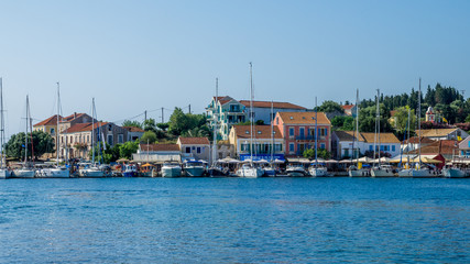Fototapeta na wymiar FISKARDO TOWN, KEFALONIA ISLAND, GREECE - JULY 12, 2015: Bay of Fiskardo with boats and yachts. Port of Fiskardo on Kefalonia island, Greece.