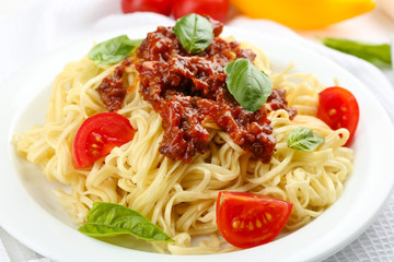 Spaghetti Bolognese on white plate, on color wooden background