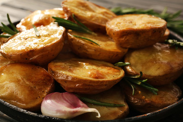 Delicious baked potato with rosemary in frying pan close up