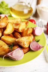 Baked potato wedges on wooden table, closeup