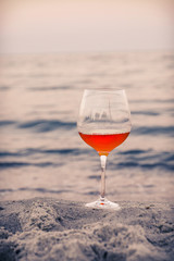 Romantic glass of wine sitting on the beach at colorful sunset