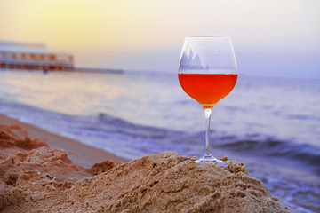 Romantic glass of wine sitting on the beach at colorful sunset