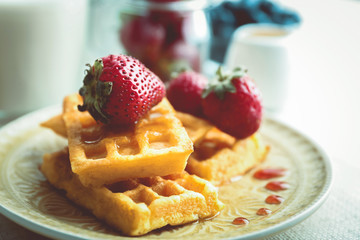 Sweet homemade waffles with fresh strawberries on plate, on light background