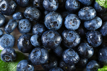 Tasty ripe blueberries with green leaves close up