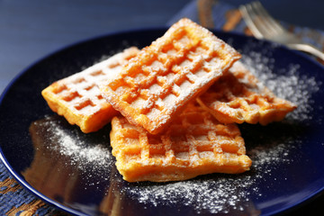 Sweet homemade waffles on plate, on dark wooden background