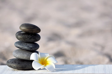 Obraz na płótnie Canvas Spa stones with flower on sand beach close up