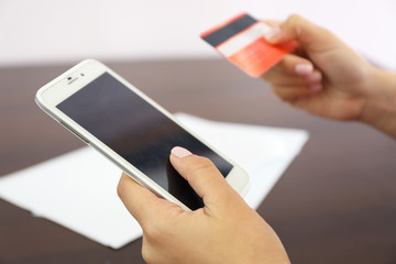 Woman verifies account balance on smartphone with mobile banking application on wooden table background