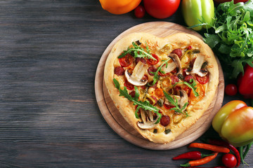 Heart shaped pizza and fresh vegetables on wooden background