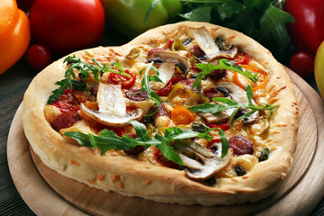 Heart shaped pizza and fresh vegetables on wooden background