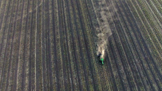 Aerial: Tractor plowing the soil on sunset